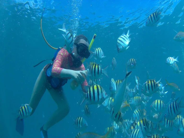 Private SNUBA guest surrounded by colorful tropical fish in clear Sint Maarten water