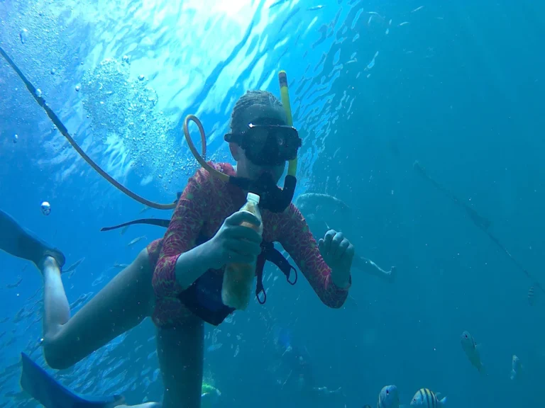 SNUBA Adventure guest giving a thumbs up in bright clear water with tropical fish